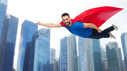 Image showing happy man in red superhero cape flying over city