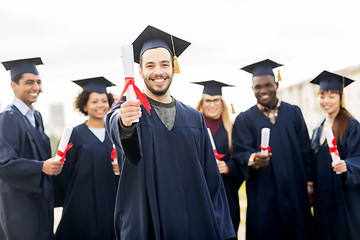 Image showing happy students in mortar boards with diplomas