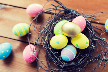 Image showing close up of colored easter eggs in nest on wood