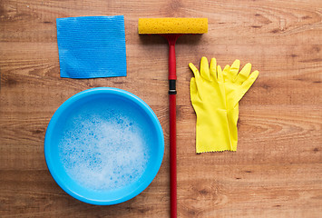 Image showing basin with cleaning stuff on wooden background