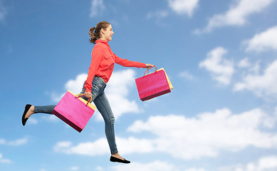 Image showing smiling young woman with shopping bags running