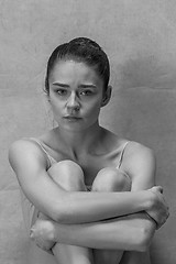 Image showing Tired ballet dancer sitting on the wooden floor on a pink background