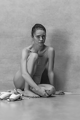 Image showing Tired ballet dancer sitting on the wooden floor on a pink background