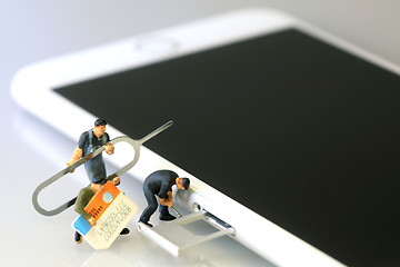 Image showing Miniature Workers Installing a SIM Card on a Smart Phone