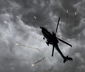 Image showing Silhouette of an attack helicopter firing flares