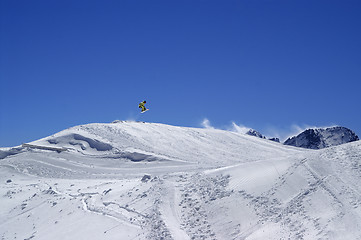 Image showing Snowboarder jumping in terrain park at ski resort on sun wind da