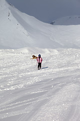 Image showing Little skier on ski slope at sun winter day and gray sky before 