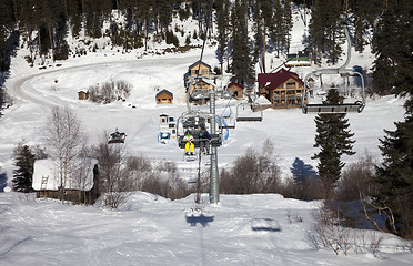 Image showing Skiers on chair-lift at ski resort in sun winter day