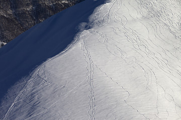 Image showing Off piste slope with track from ski and snowboard in sun evening
