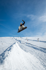 Image showing Snowboarder jumping against blue sky