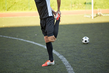Image showing soccer player stretching leg on field football