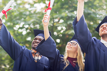 Image showing happy students in mortar boards with diplomas