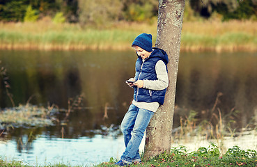 Image showing happy boy playing game on smartphone outdoors