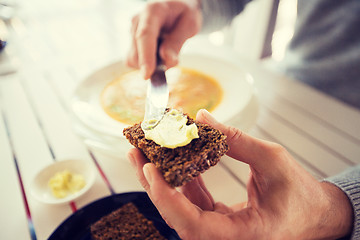 Image showing close up of hands applying butter to bread