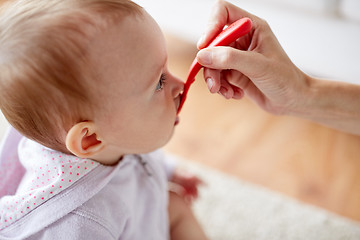 Image showing hand with spoon feeding little baby at home