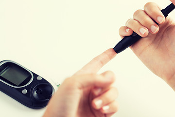 Image showing close up of woman making blood test by glucometer