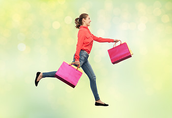 Image showing smiling young woman with shopping bags running