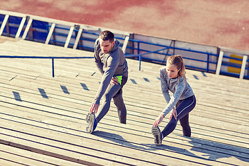 Image showing couple stretching leg on stands of stadium