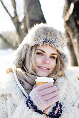 Image showing young pretty teenage hipster girl outdoor in winter snow park having fun drinking coffee, warming up happy smiling, lifestyle people concept