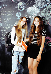Image showing back to school after summer vacations, two teen real girls in classroom with blackboard painted together