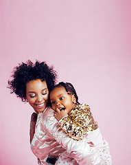 Image showing young pretty african-american mother with little cute daughter hugging, happy smiling on pink background, lifestyle modern people concept