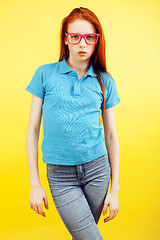 Image showing young pretty red hair teenage hipster girl posing in glasses emotional happy smiling on yellow background, lifestyle people concept 