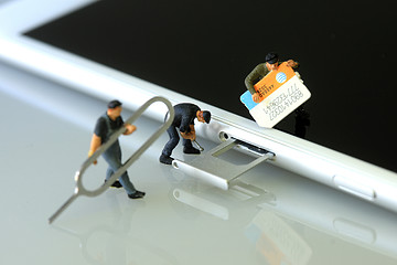 Image showing Miniature Workers Installing a SIM Card on a Smart Phone