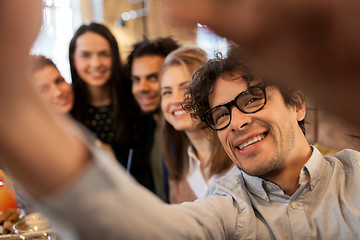 Image showing happy man taking selfie with friends at restaurant