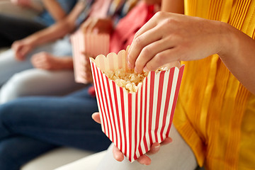 Image showing close up of happy friends eating popcorn at home