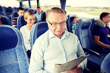 Image showing happy senior man reading newspaper in travel bus