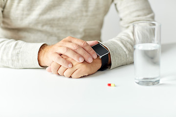 Image showing close up of senior man with water, pill and watch