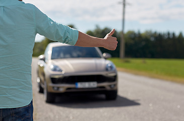 Image showing man hitchhiking and stopping car with thumbs up