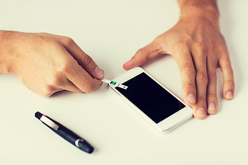 Image showing close up of man with smartphone making blood test