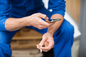 Image showing auto mechanic smoking cigarette at car workshop