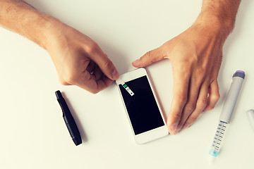 Image showing close up of man with smartphone making blood test