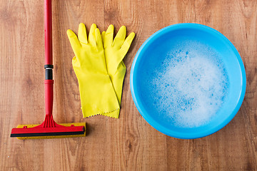 Image showing basin with cleaning stuff on wooden background