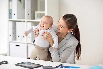 Image showing happy businesswoman with baby working at office