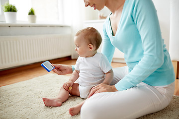 Image showing happy mother showing smartphone to baby at home