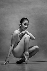 Image showing Tired ballet dancer sitting on the wooden chair on a gray background