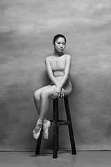 Image showing Tired ballet dancer sitting on the wooden chair on a pink background