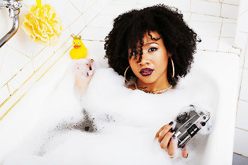 Image showing young afro-american teen girl laying in bath with foam, wearing 