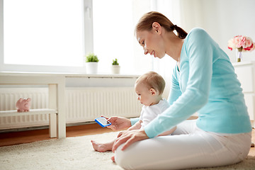 Image showing happy mother showing smartphone to baby at home