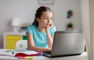 Image showing bored girl with laptop and notebook at home