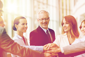 Image showing business people putting hands on top in office