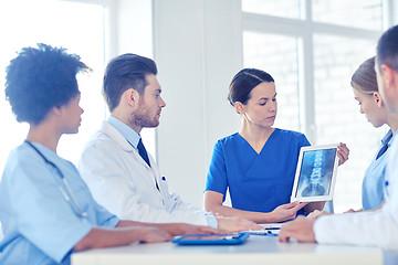 Image showing group of doctors with x-ray on tablet pc at clinic