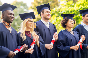 Image showing happy students in mortar boards with diplomas