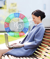 Image showing smiling woman with laptop and zodiac signs in city