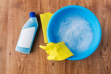 Image showing basin with cleaning stuff on wooden background