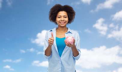 Image showing happy woman with piggy bank showing thumbs up