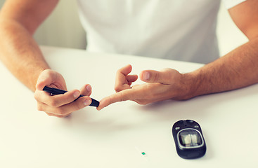 Image showing close up of man checking blood sugar by glucometer